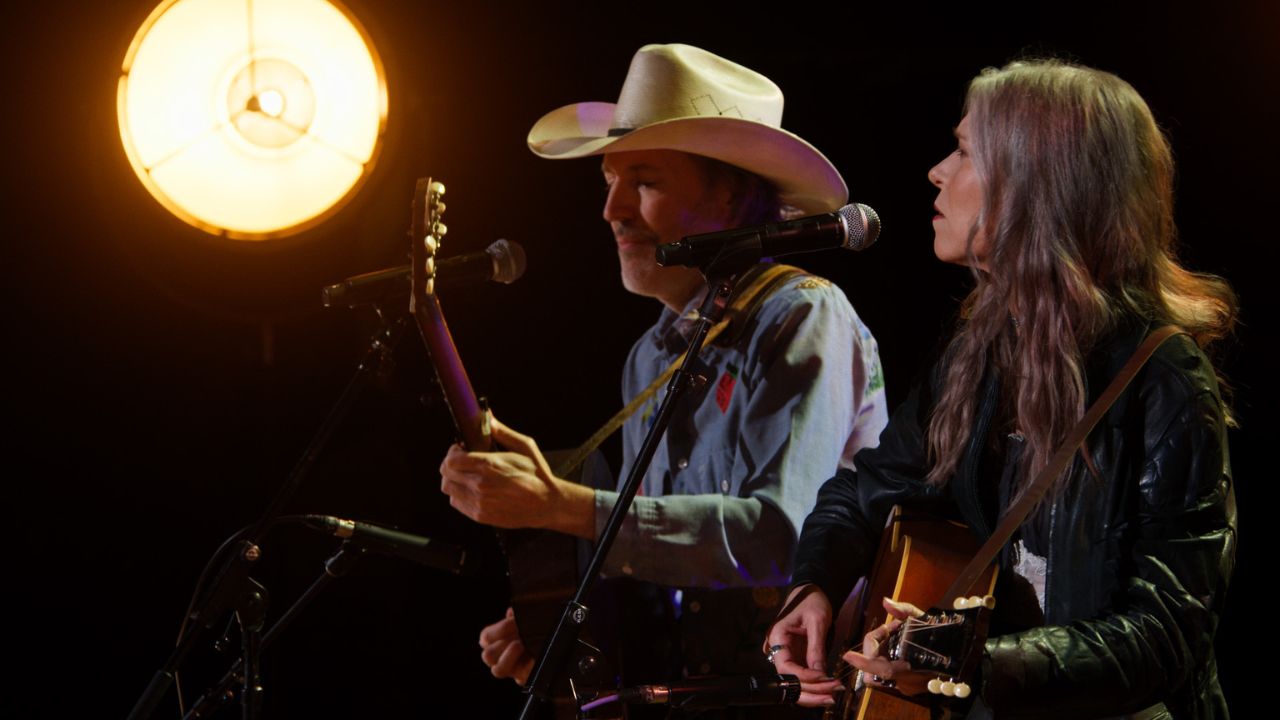 a man and woman playing guitar and singing